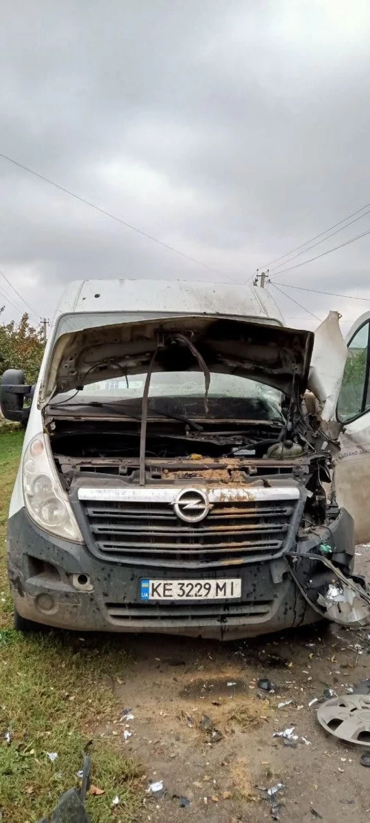 Білий мікроавтобус волонтерів із розбитою передньою частиною після удару російського дрона.