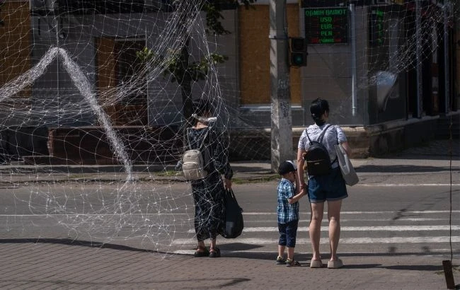 Дві жінки і дитина стоять у Слов'янську і чекають, щоб перейти дорогу, вулиці накрити антидроновими сітками