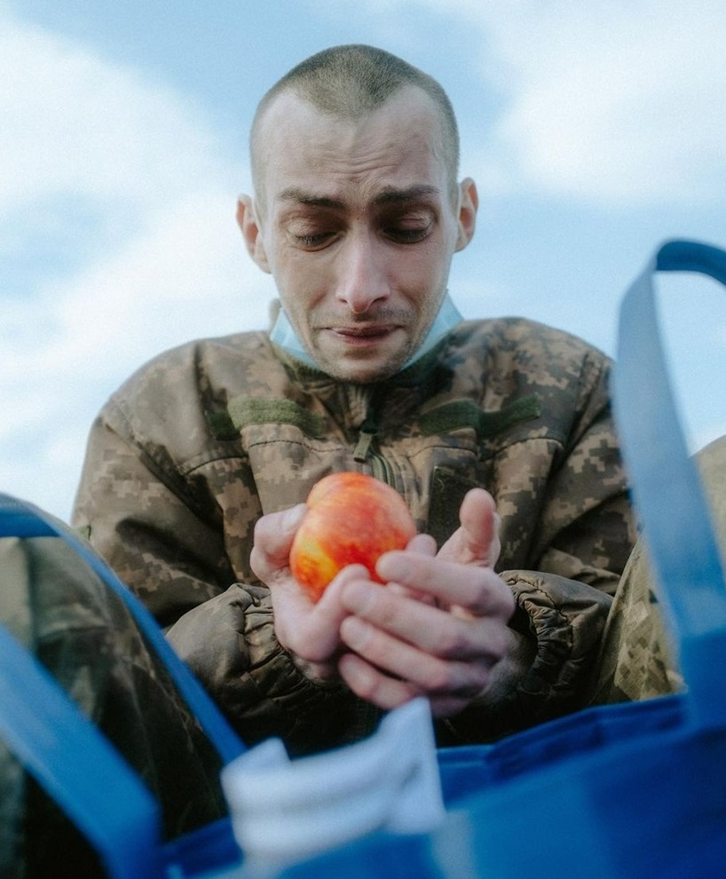 Український захисник, який щойно повернувся з російського полону, дивиться на яблуко зі сльозами на очах. Майже рік він не їв свіжих фруктів та смачної їжі.