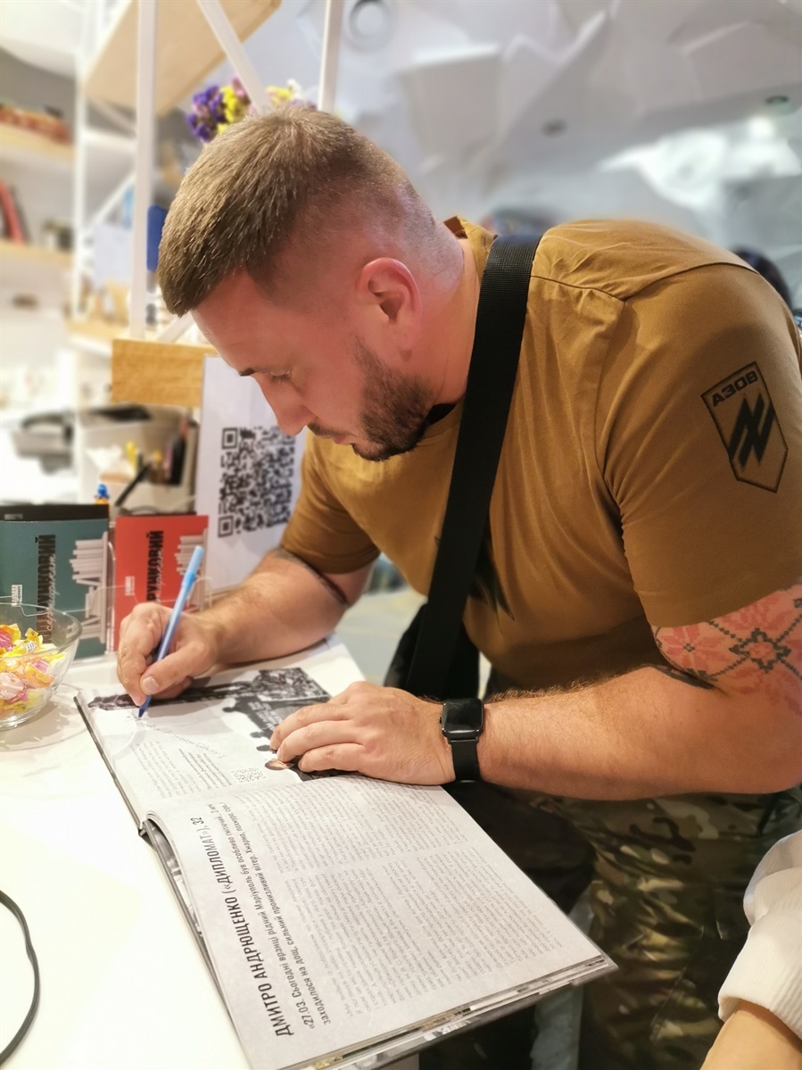 "Дипломат" підписує примірник книги "Очі Маріуполя"