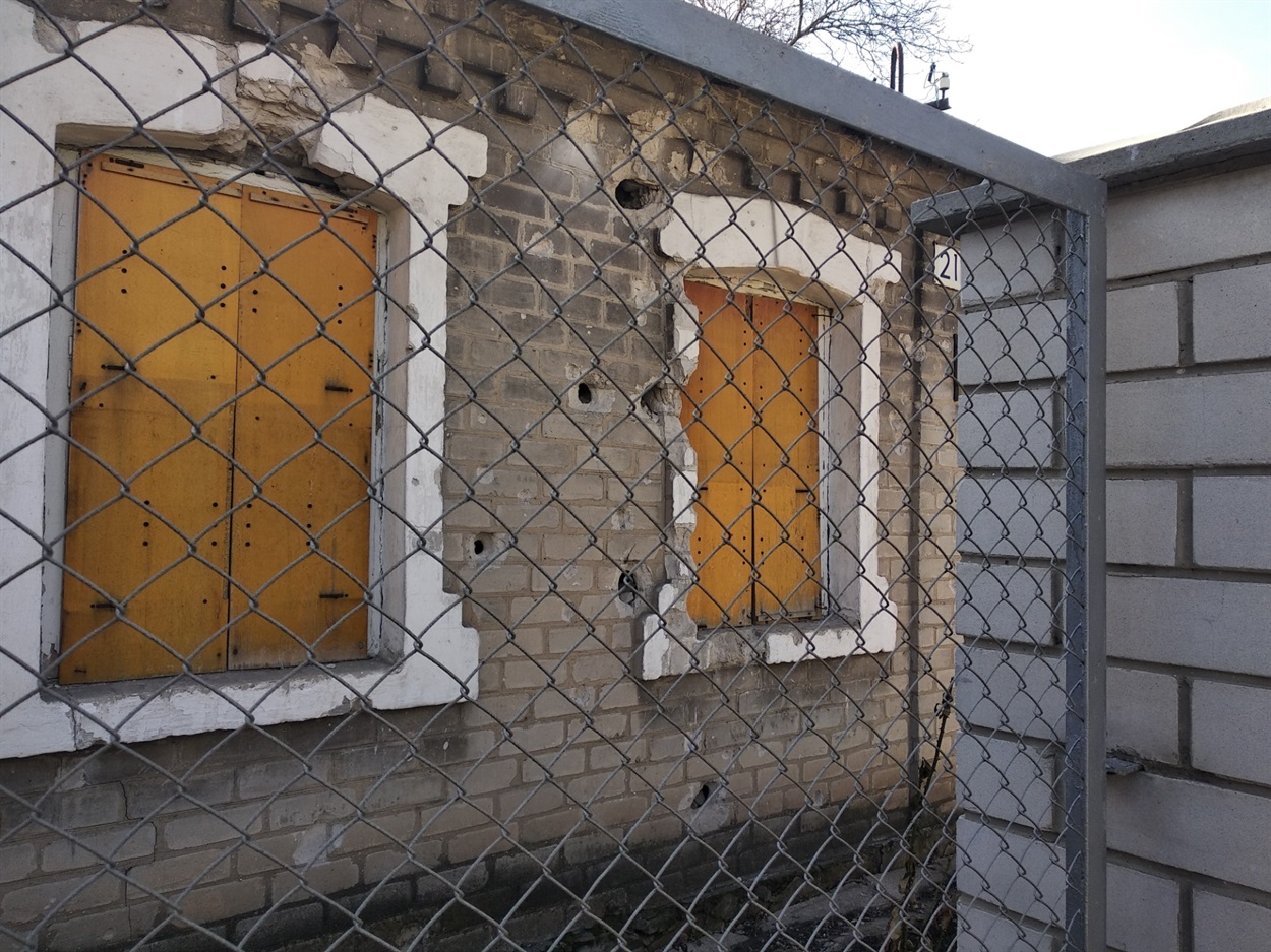 Поселок возле железнодорожного вокзала Донецка, весна 2019 года. Стена жилого дома пробита насквозь крупным калибром. В этом дом люди не вернулись