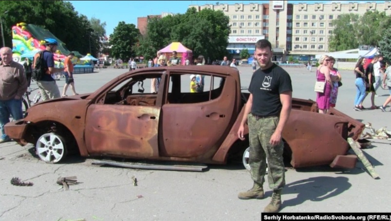 Алексей Юков возле сгоревшего в 2014 году авто на площади в Славянске