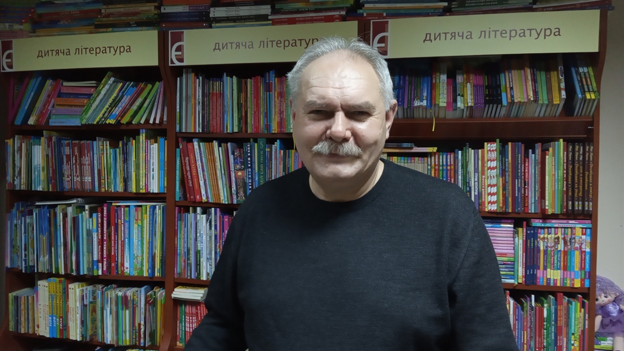 Віктор Разживін біля полиць із дитячою літературою