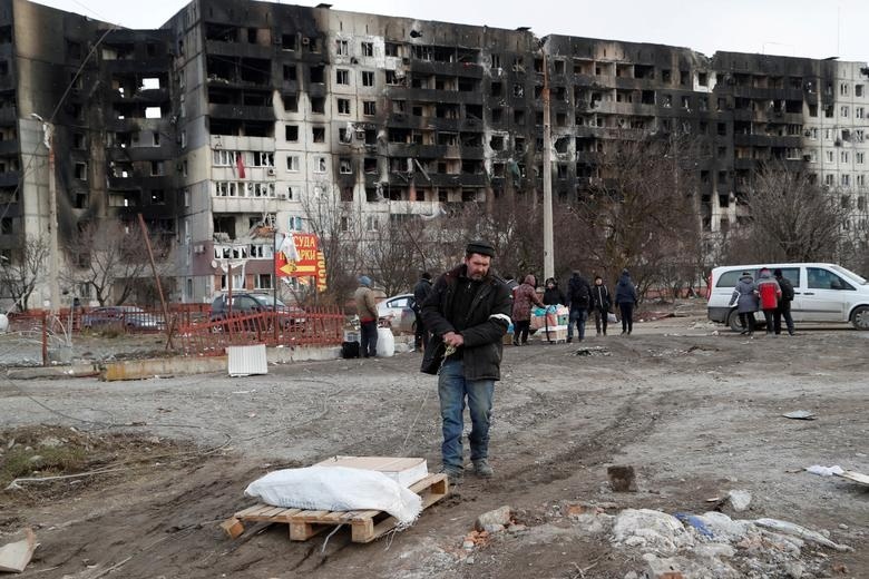 Люди собрались возле разрушенного дома в Мариуполе