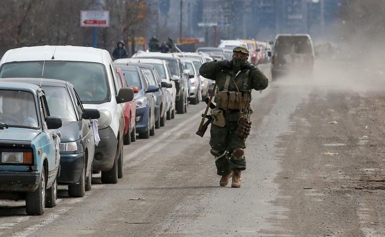 Российский военный возле очереди из машин местных жителей