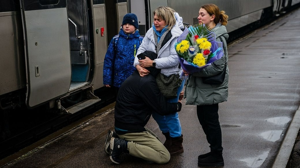 Чоловік плаче на колінах та обіймає своїх рідних, які повернулися додому в Краматорськ. Родина не бачилася понад рік.