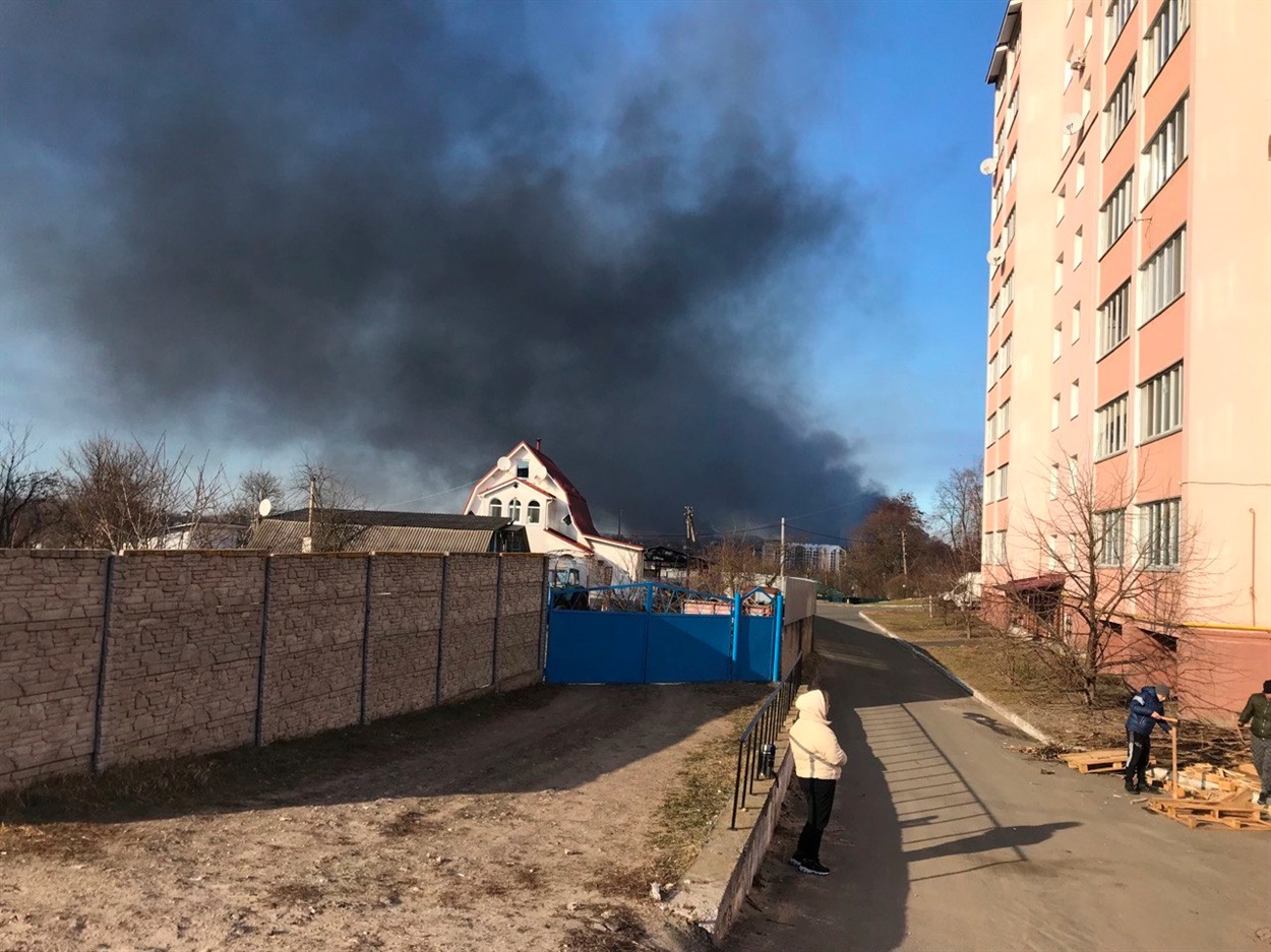 Донька Лесі Настя (у світлому одязі) дивиться, як горить аеропорт в Гостомелі. Праворуч будинок в Бучі, де вони були в підвалі