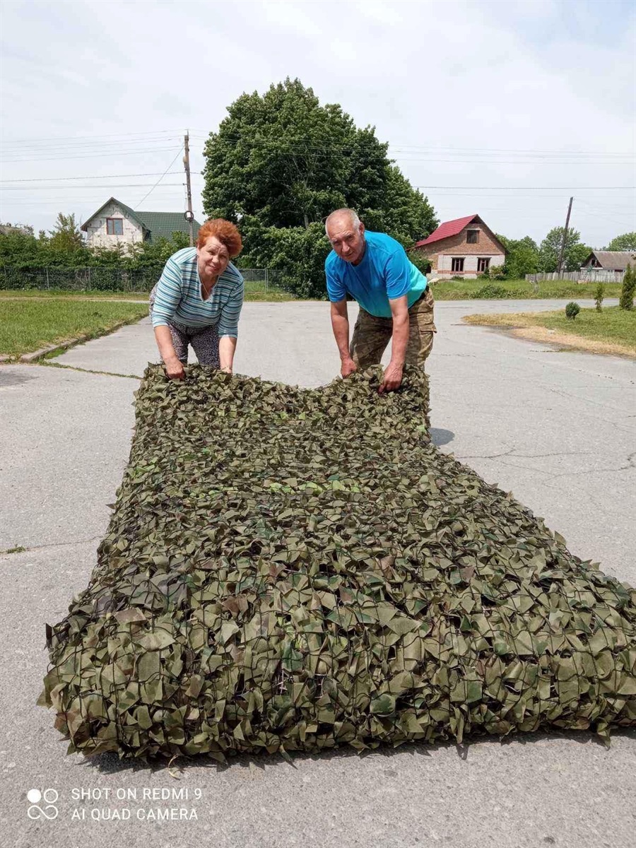 Віра та Олександр з маскувальною сіткою їхнього виробництва для ЗСУ