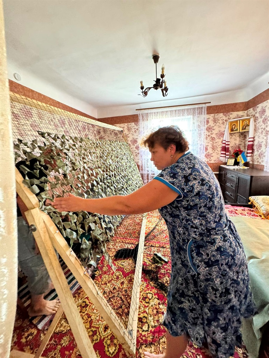 Пані Віра демонструє рамку для плетіння сіток в себе вдома